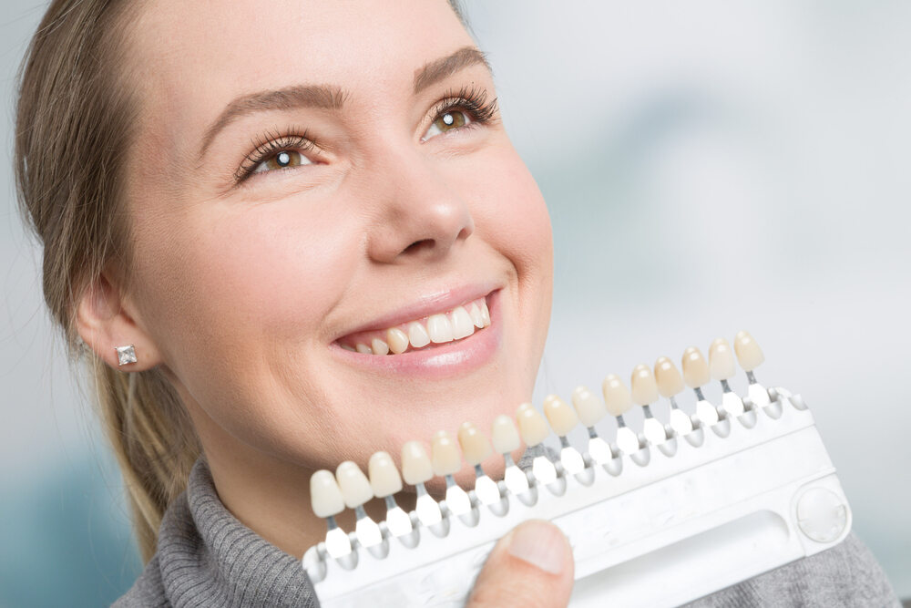 a woman is choosing the right shed of porcelain veneers